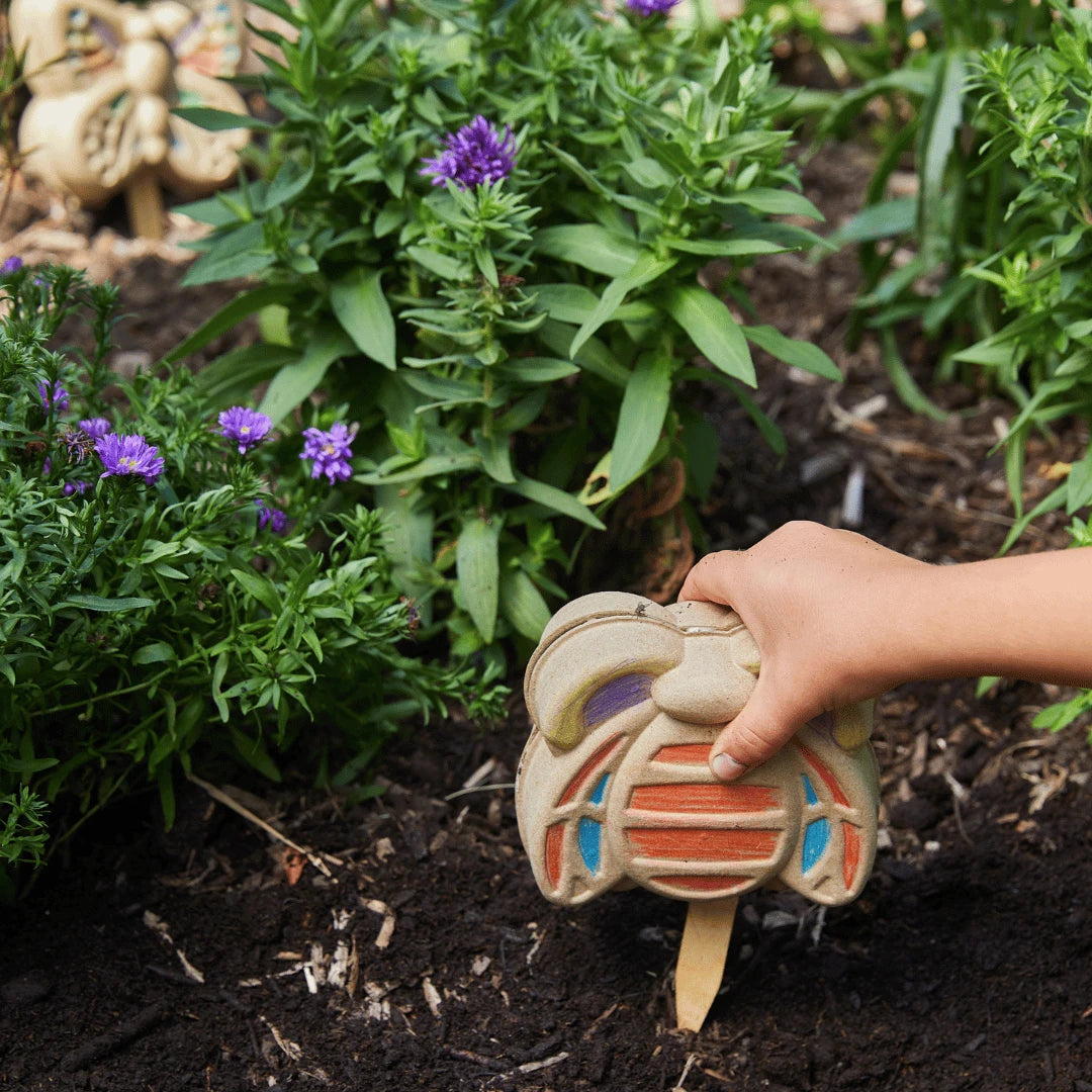 Colored bumble bee activity kit being placed in a garden.