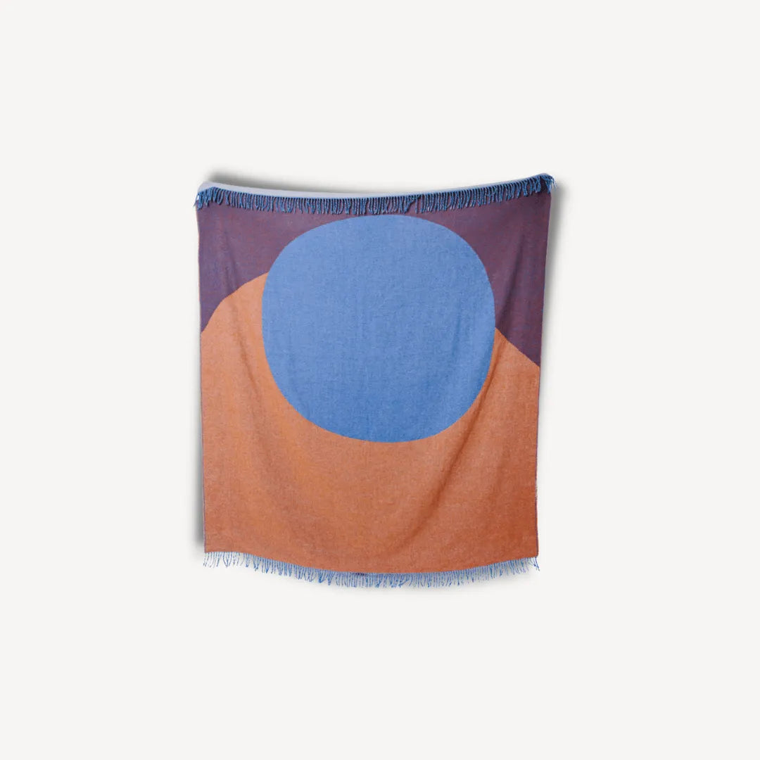 Purple and orange wool blanket with a blue circle in the middle.