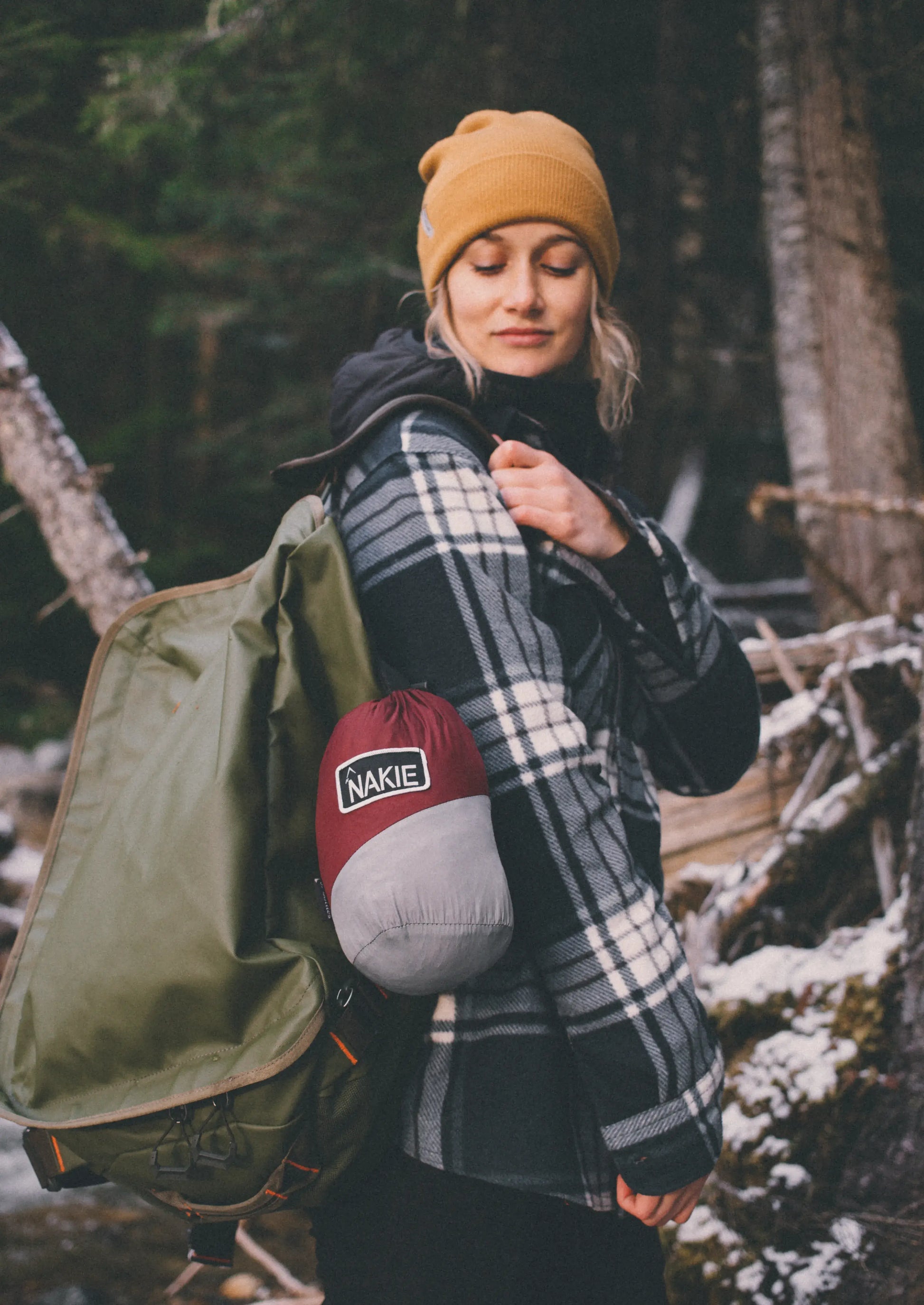 Woman outside hiking with a red and gray hammock bag.
