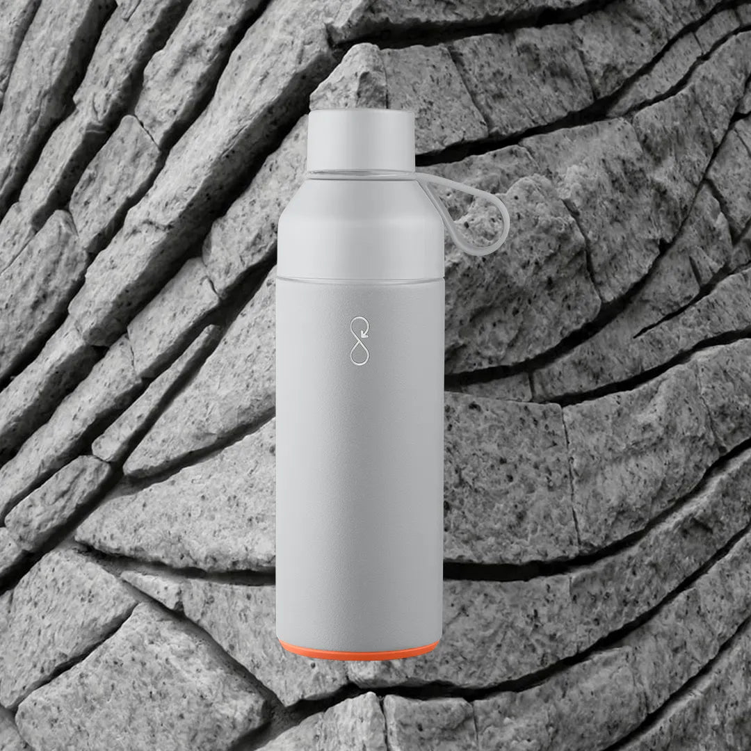 Gray water bottle in front of a rock background.