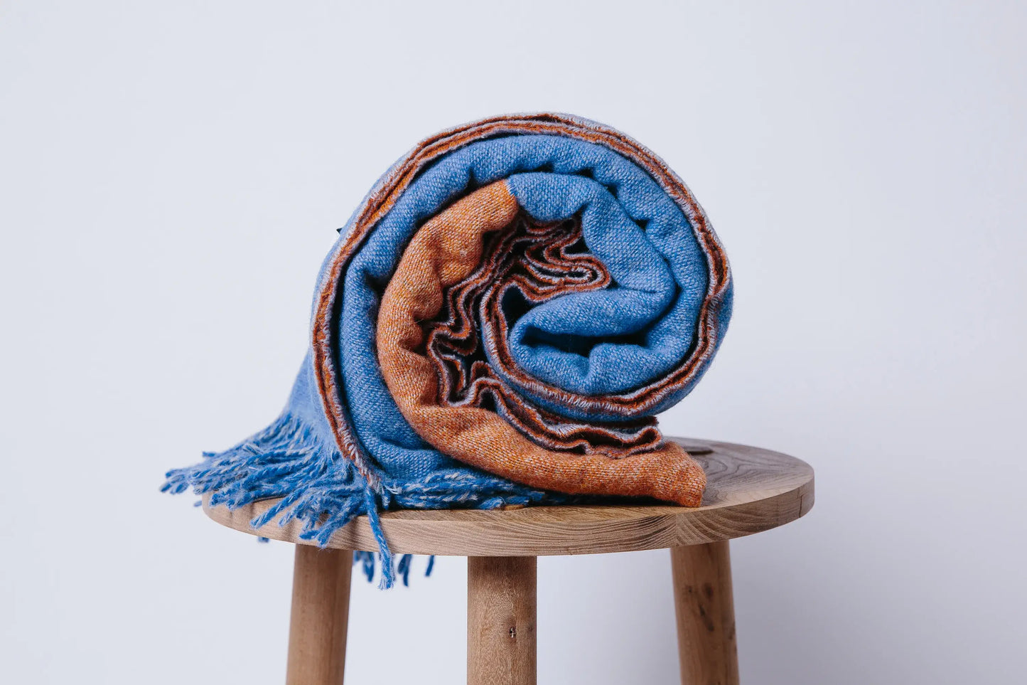 Blue and orange wool blanket rolled up on a stool.