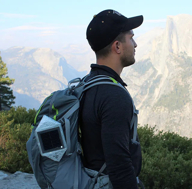 Man hiking outside with a backpack and lantern attached.