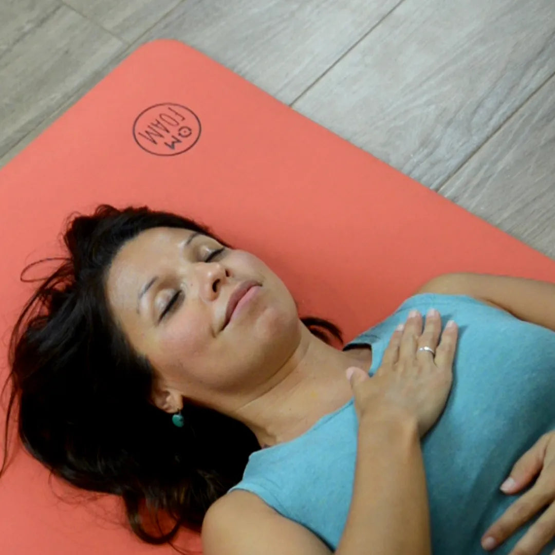 Woman lying down on a red yoga mat.
