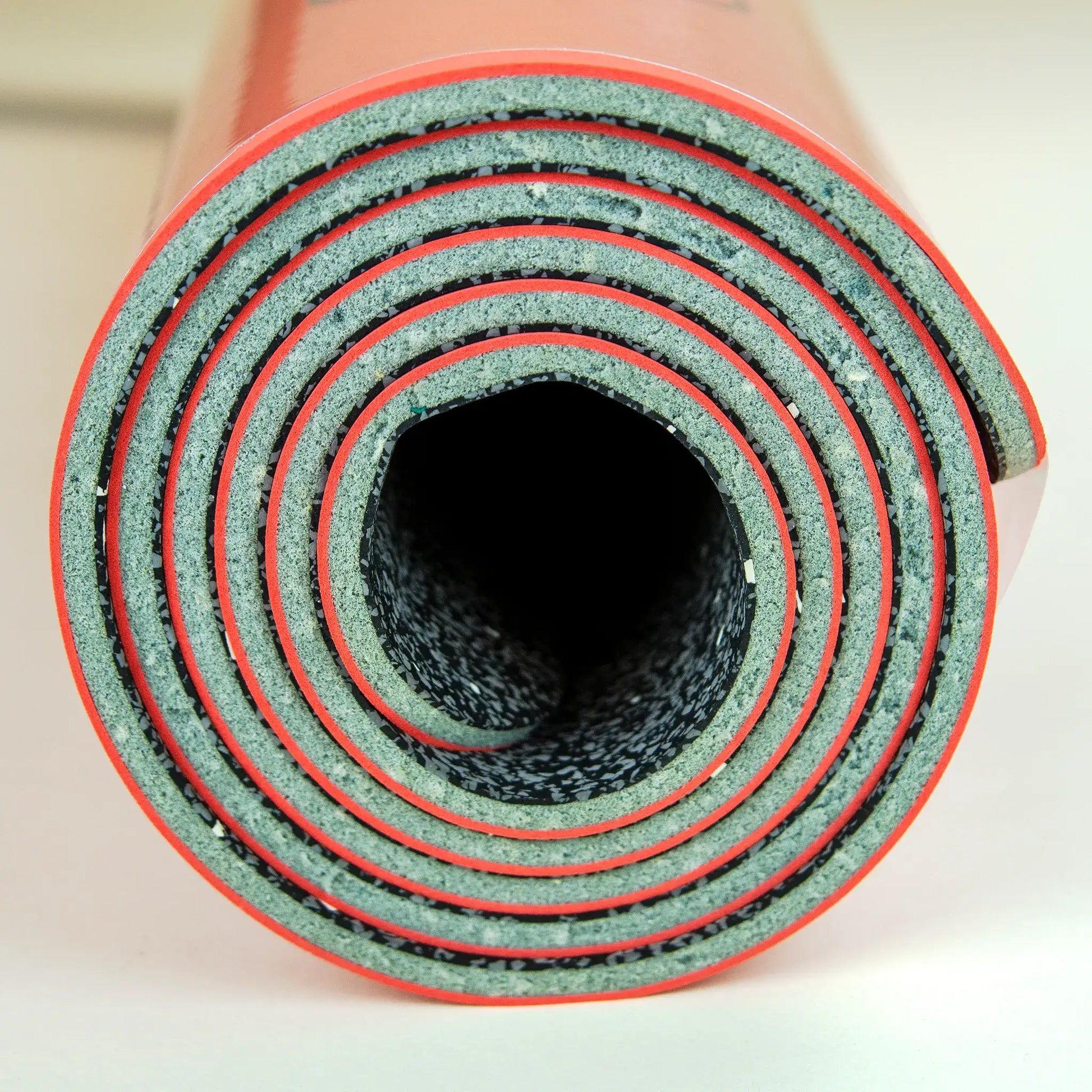 Side profile of a rolled up red yoga mat.