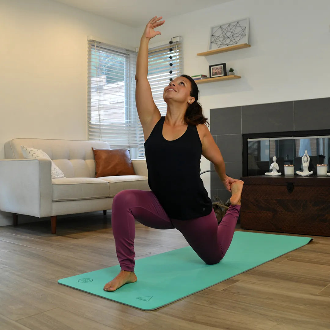 Woman doing a yoga pose on a teal yoga mat.