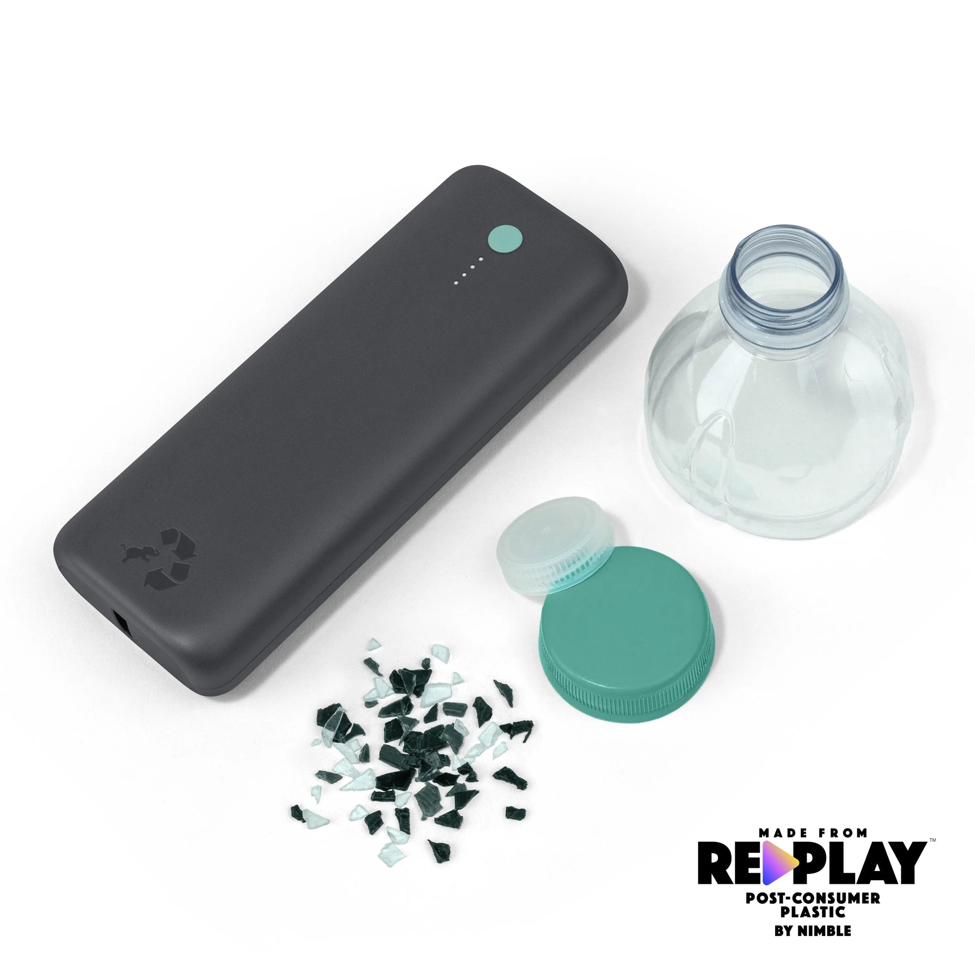 Large dark gray portable charger with green button next to bottle caps and shredded plastic.
