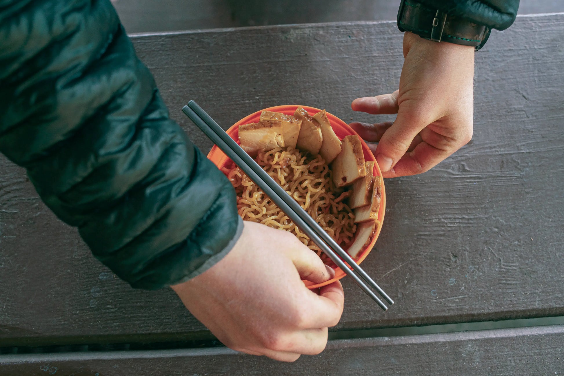 Person moving a bowl of food with chopsticks on top.