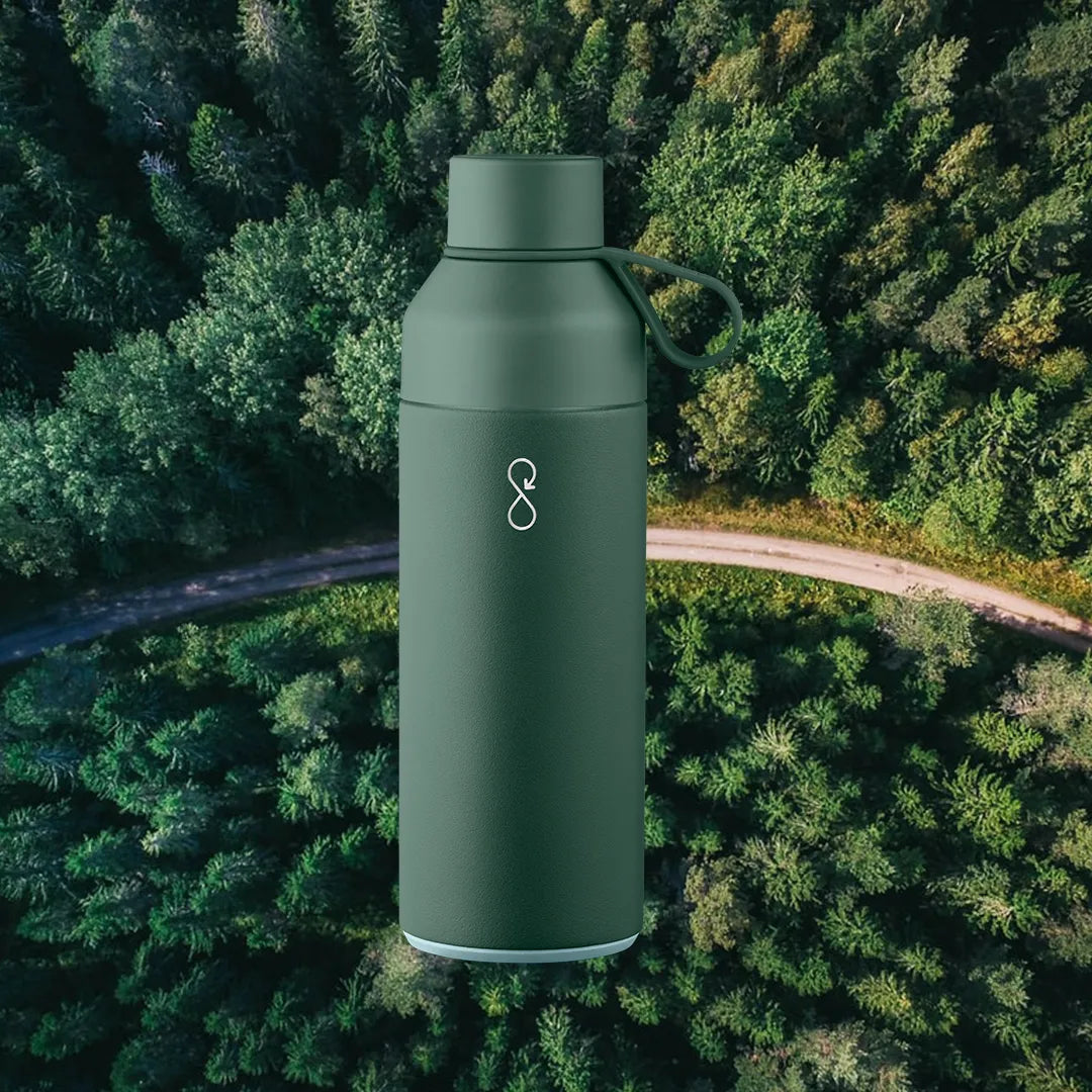 Green water bottle in front of a forest background.