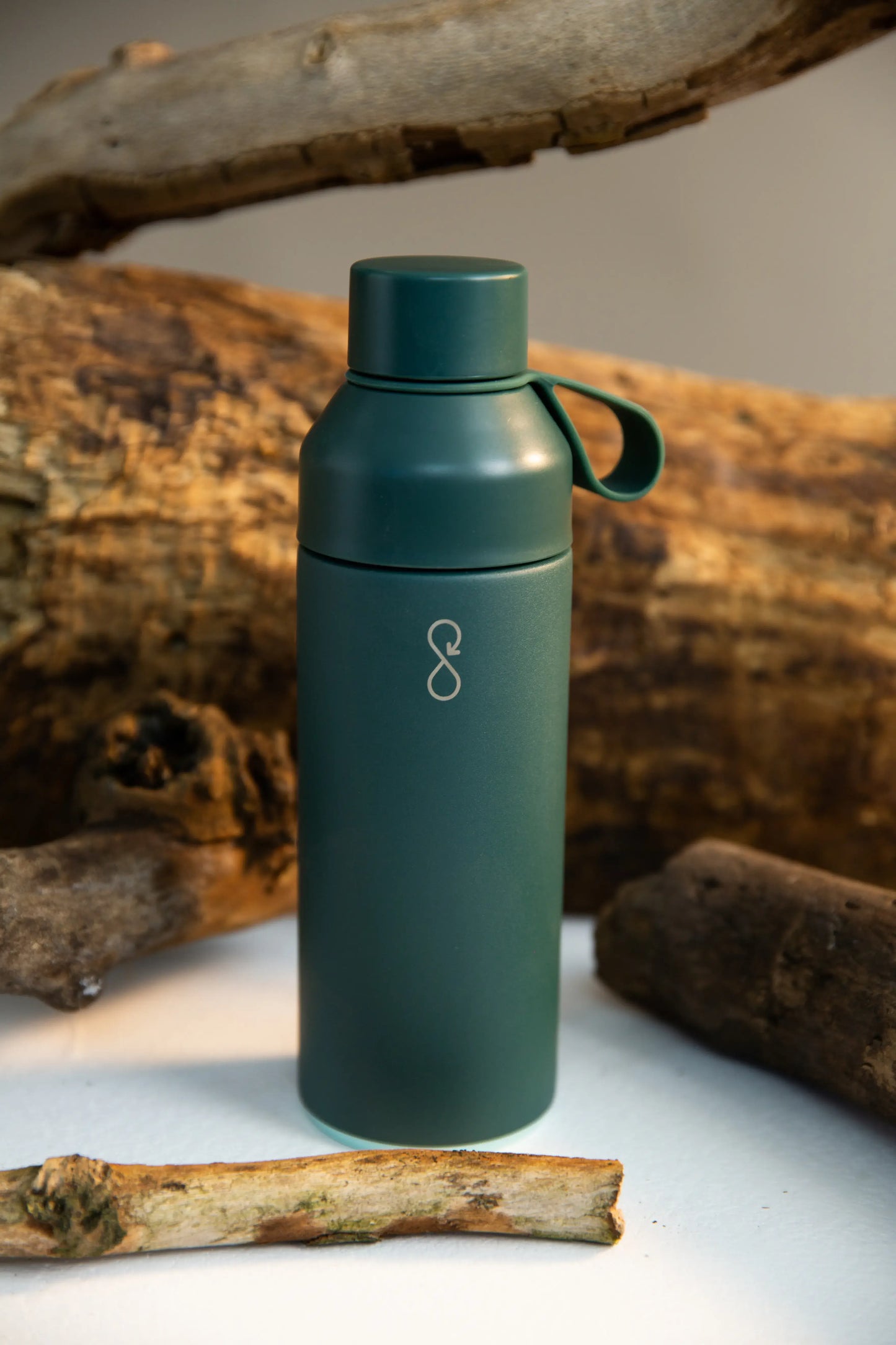 Forest green water bottle next to some wood.