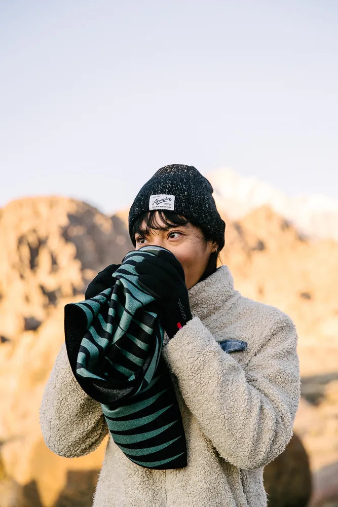 Woman outside holding a mini towel with teal and black lines.