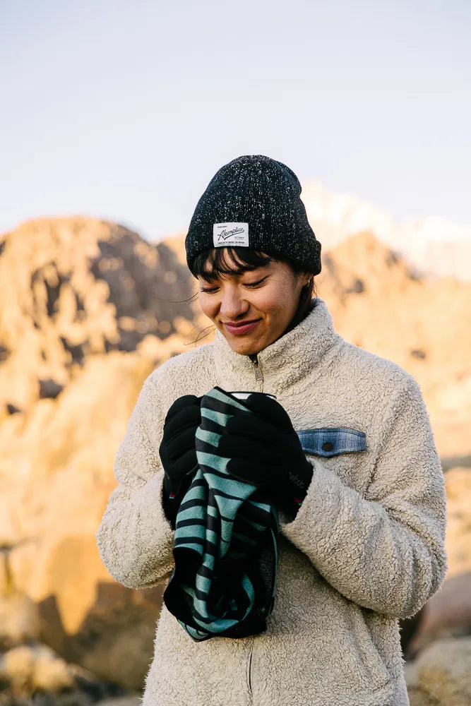 Woman outside holding a mini towel with teal and black lines.