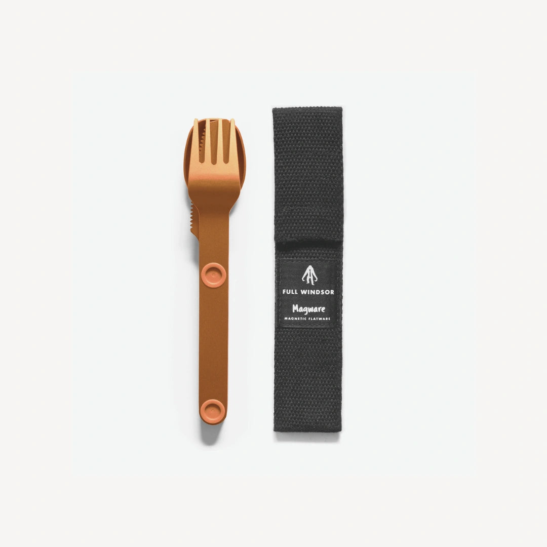 Orange fork, spoon and knife connected next to black case.