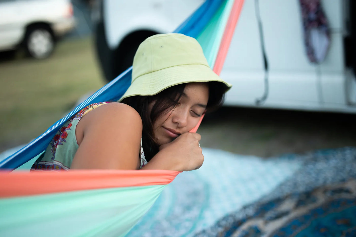 Woman sleeping in a sky blue and orange hammock.