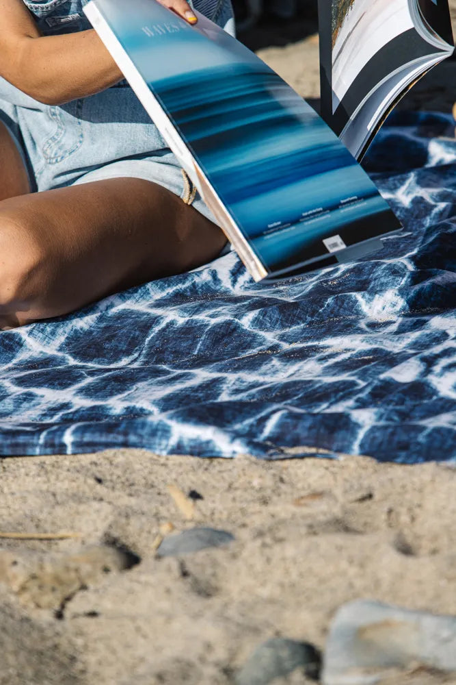 Closeup of a blue and white outdoor blanket on the beach.