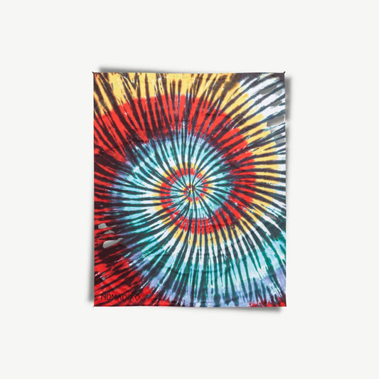 Blue,red, yellow and white tie-dye outdoor blanket spread out.