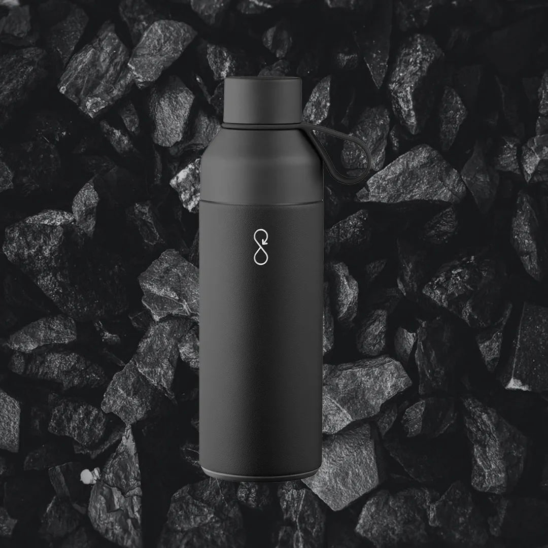 Black water bottle in front of coal background.