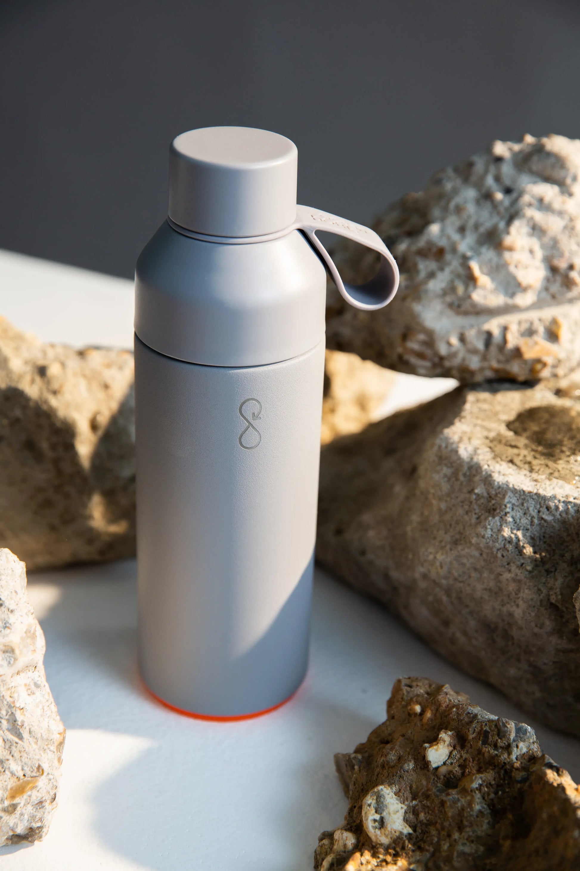 Gray water bottle next to some rocks.