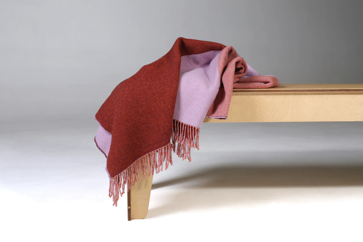 Red and pink wool blanket on edge of table.