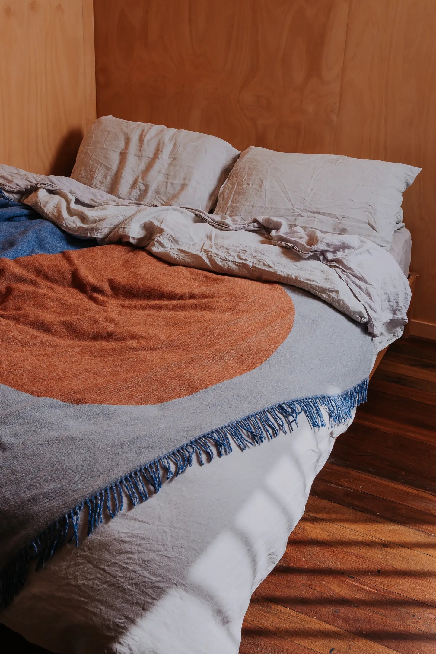 Ble, gray and orange wool blanket on a bed.