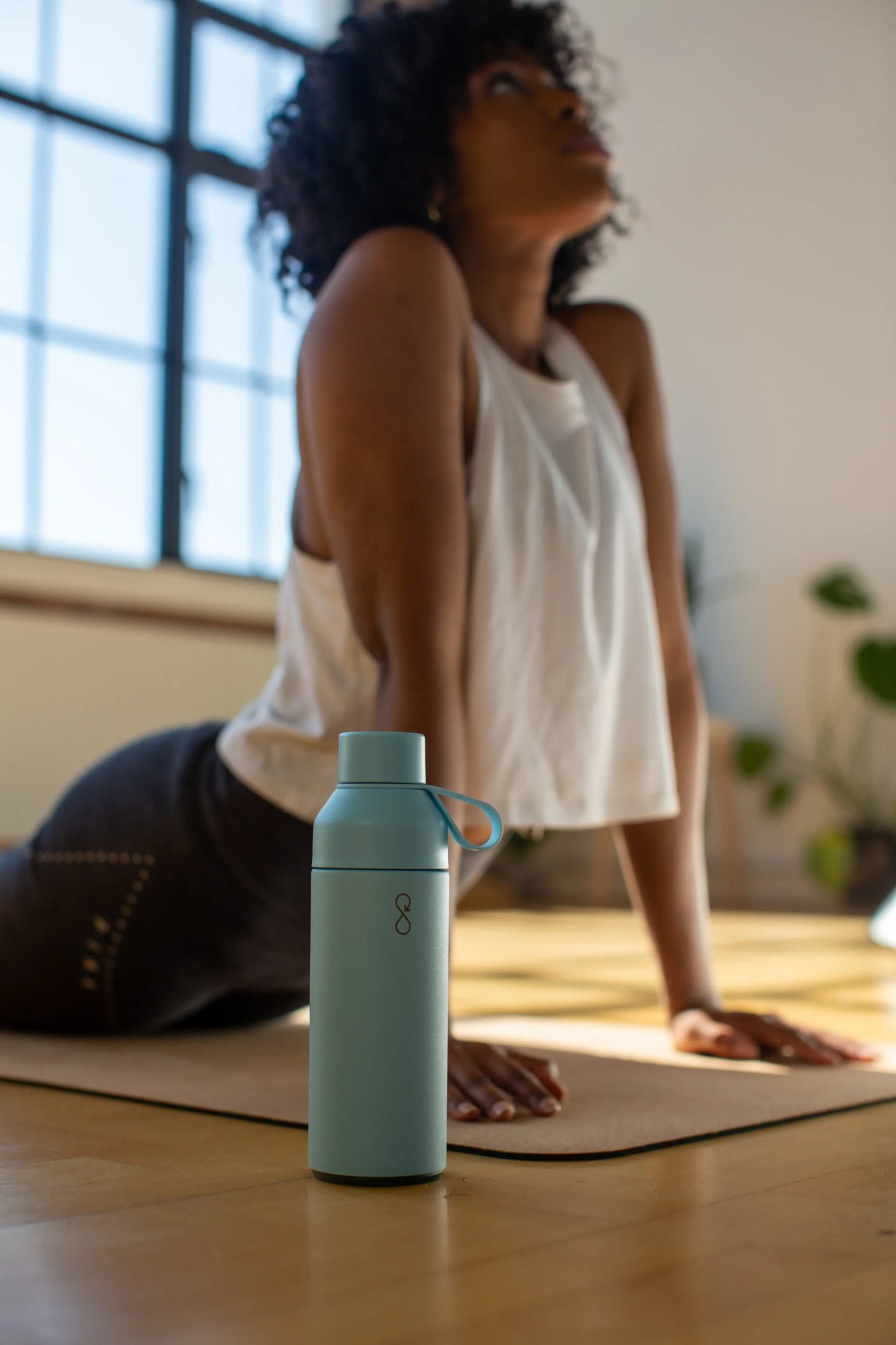 Woman doing yoga next to a blue water bottle.