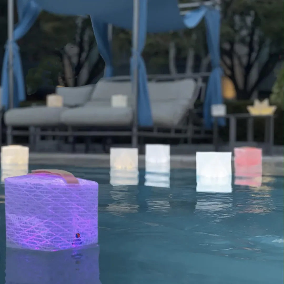 Multiple cube lanterns of different colors floating in a pool.