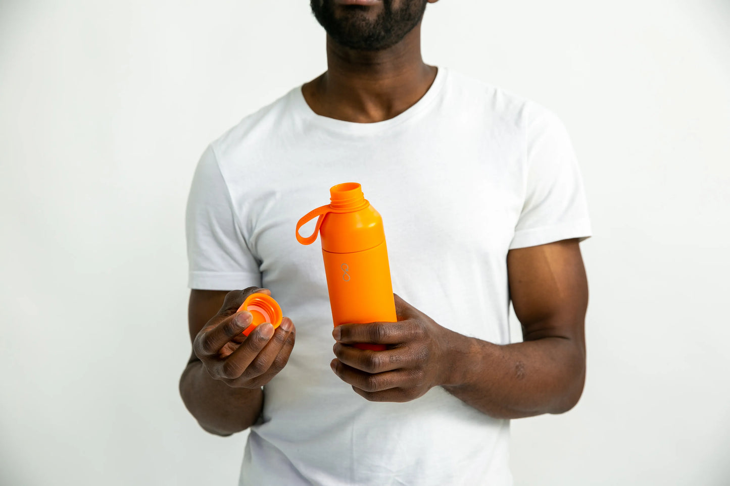 Man holding a orange water bottle with the lid off.