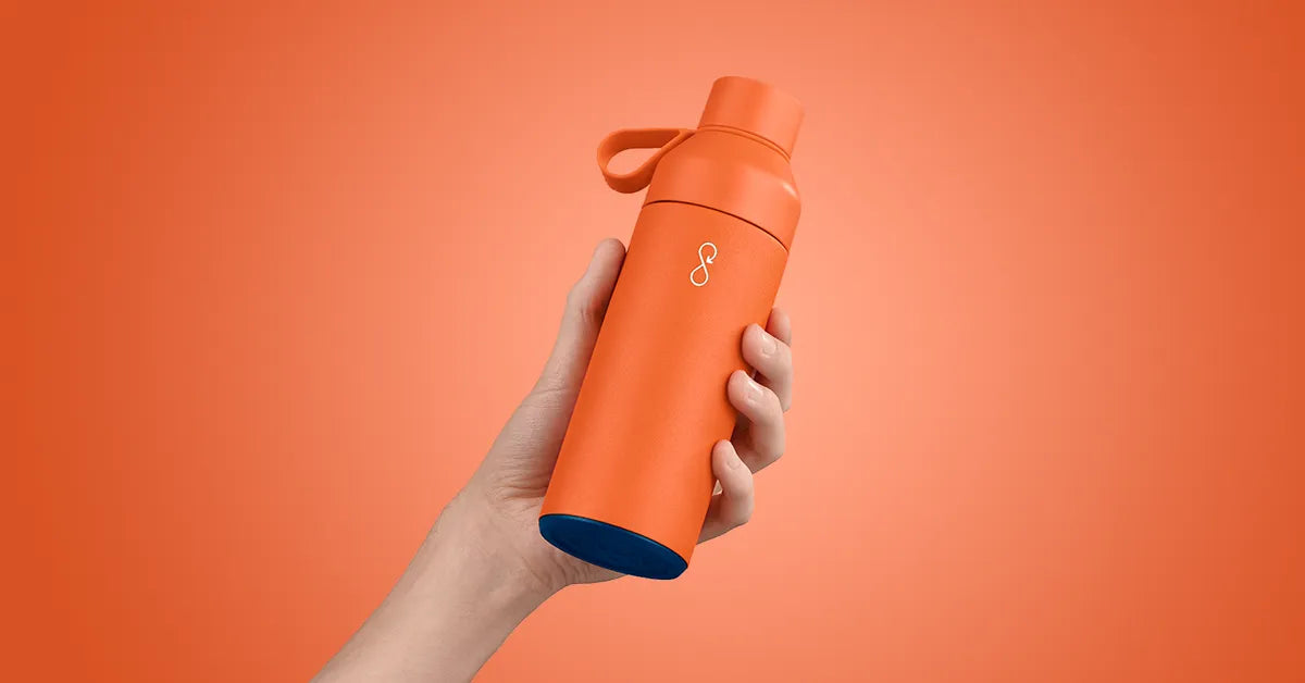 Hand holding an orange water bottle.