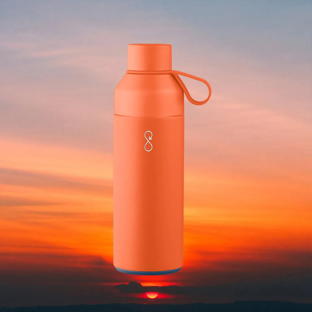 Orange water bottle in front of a sunset.