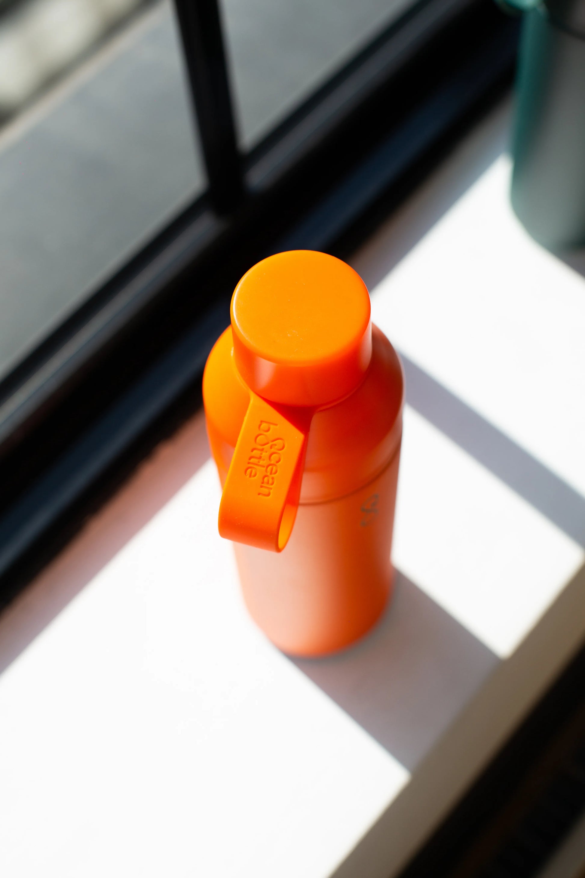Top of an orange water bottle on a window sill.