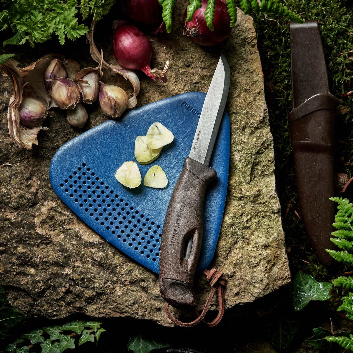 Brown knife on a blue cutting board next to food.