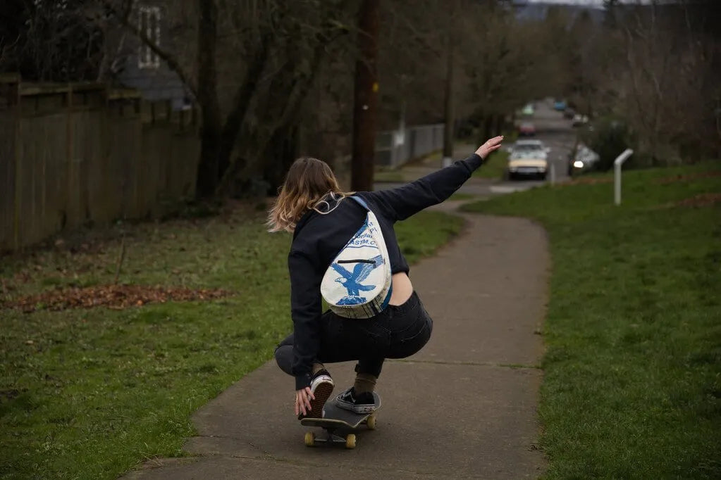 Skateboarder wearing a sling bag with eagle on it.
