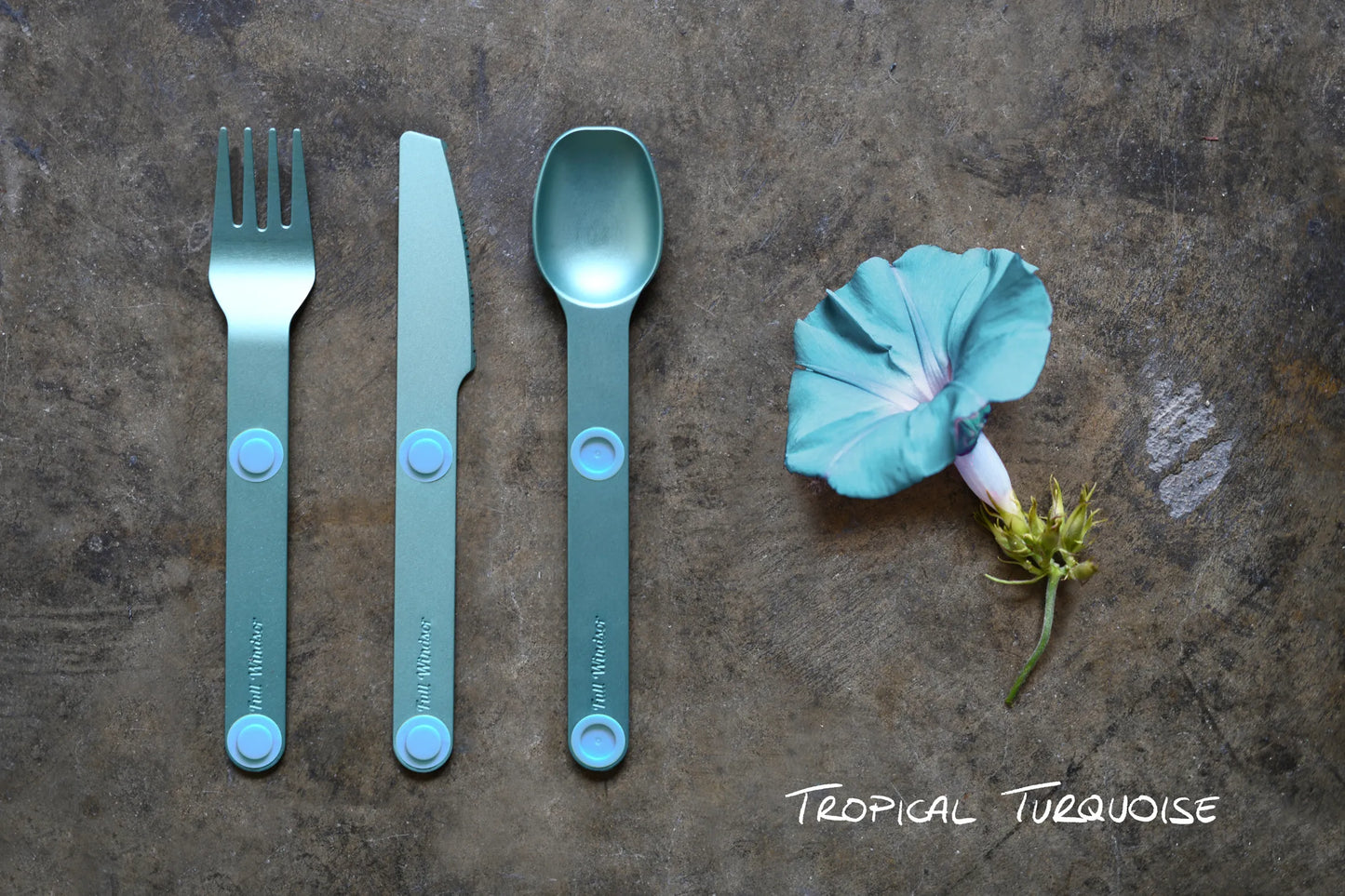 Turquoise fork, knife and spoon next to turquoise flower.