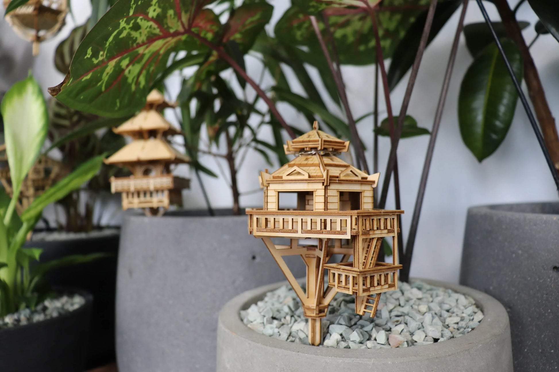 Two small wooden treehouses in potted plants.