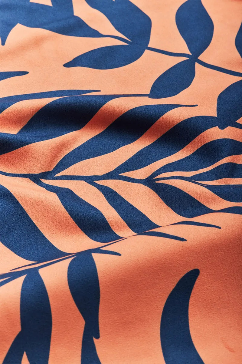 Close up of orange towel with navy blue leaves.