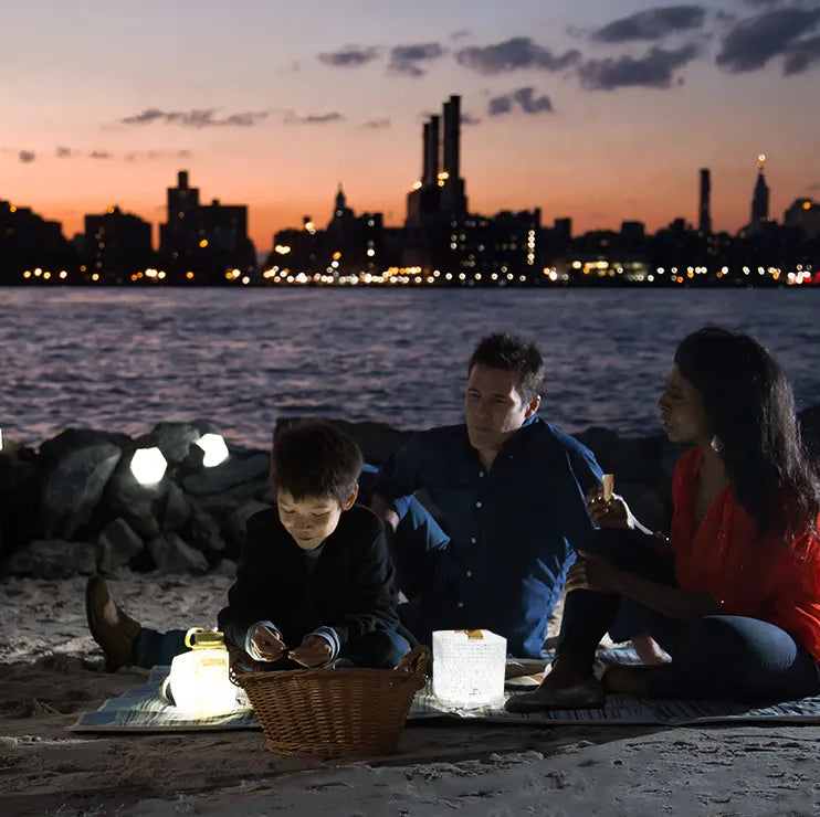 Family sitting on the beach next to some lanterns.