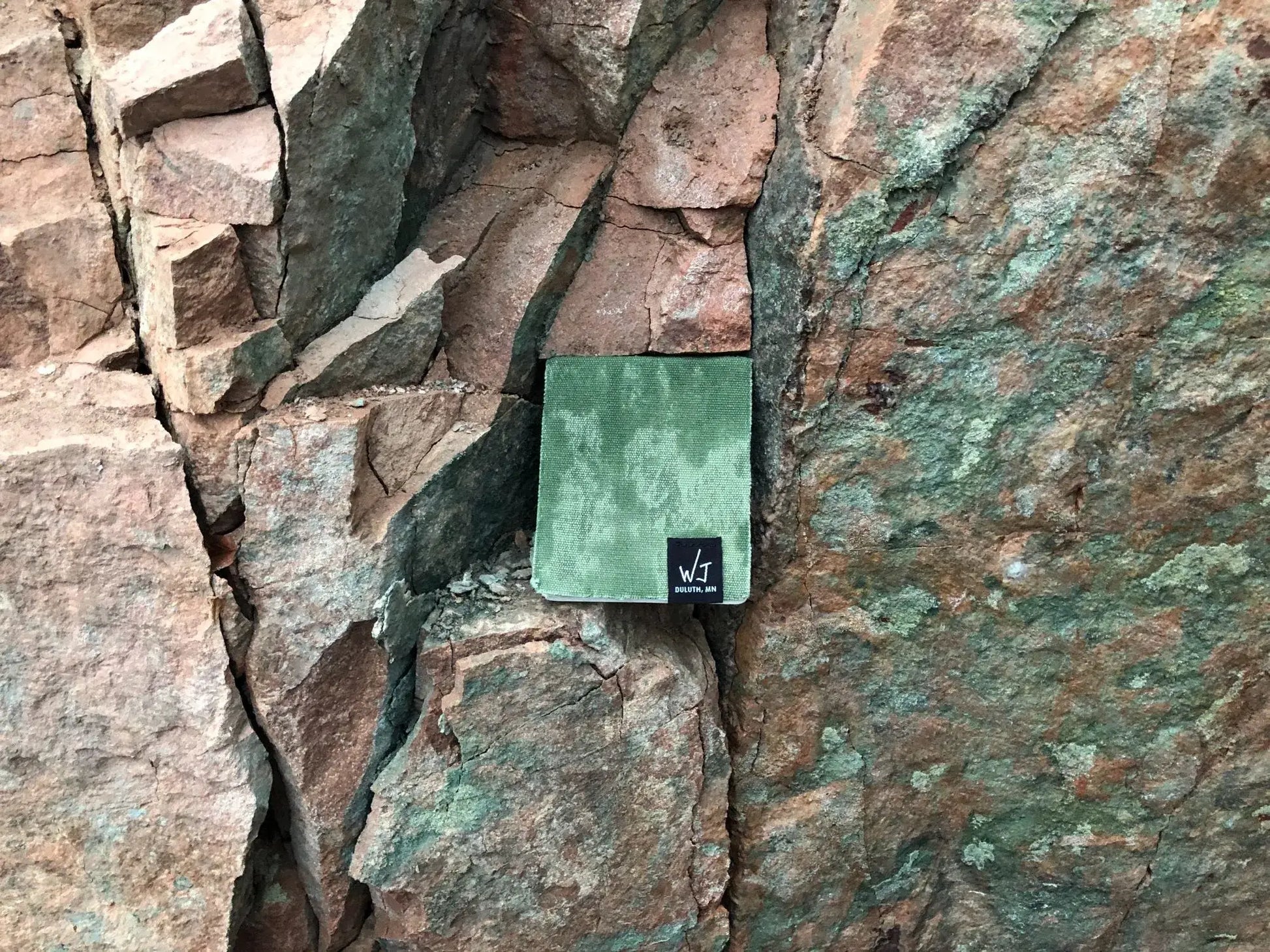 Green notepad on a rock wall.