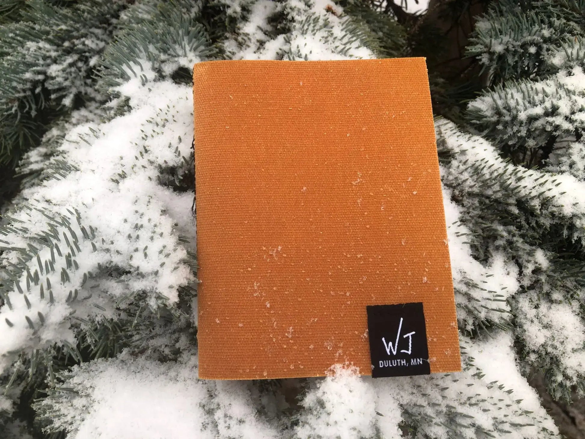 Yellow notebook on a snow covered pine tree.