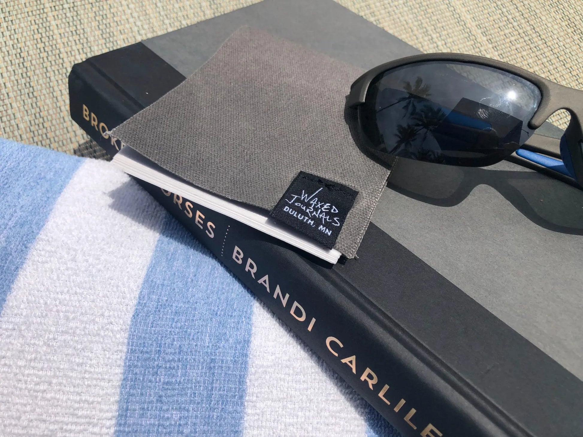 Gray notepad on a book next to sunglasses.