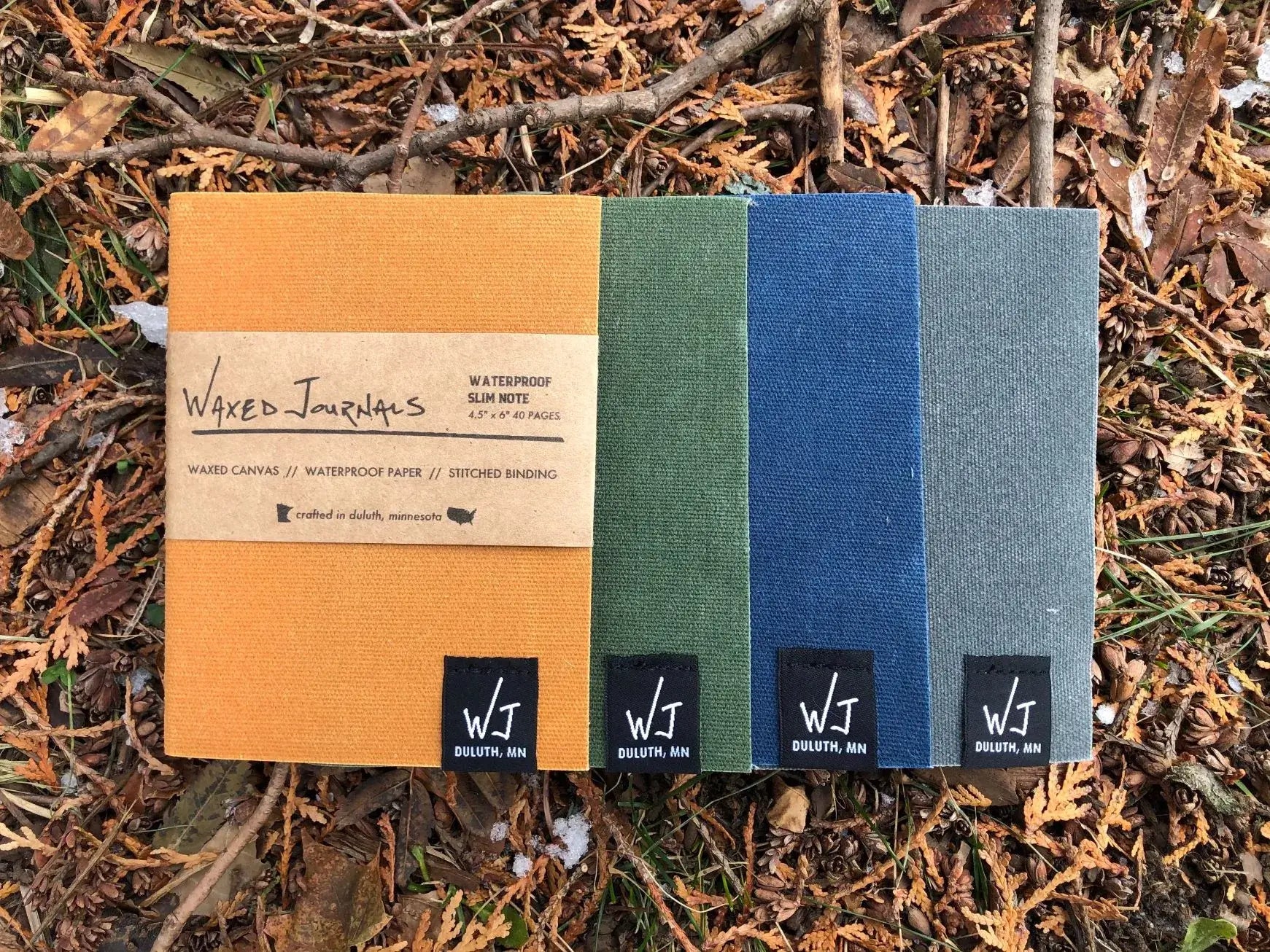Multiple colors of waxed journal notebooks outside.
